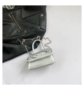 Detail of silver metallic mini bag with bow accents and elegant chain shoulder strap