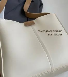Dettaglio borsa a secchiello bianco crema con rifiniture in pelle marrone e logo