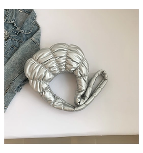 Detail view of silver crescent bag with pleated puffer design and metallic texture