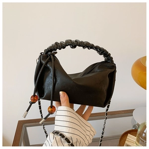 Détail d'un sac à main plissé noir avec cordon en perles d'ambre et bandoulière en chaîne