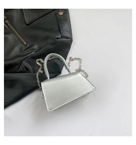Detail of silver metallic mini handbag with chain strap and sleek trapezoid structure