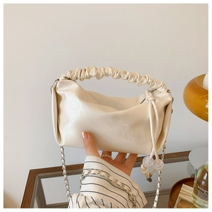 Détail du sac à main plissé blanc cassé avec gaufrage floral et cordon de serrage