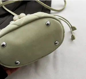 Détail du fond d'un sac seau vert avec rivets métalliques de protection et surpiqûres
