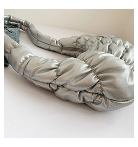 Detail of silver pleated cloud bag featuring soft quilted texture and metallic finish