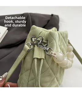 Détail d'un sac seau matelassé vert clair avec anse en perles et crochet en métal argenté