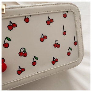 Detalle de neceser blanco de cuero PU con estampado de cerezas y cremallera dorada