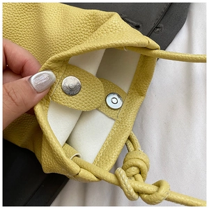 Detail of yellow lychee leather bag showing magnetic closure and knotted strap