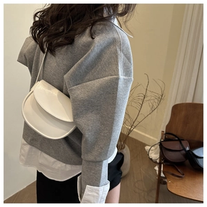 Close-up of a white leather saddle bag with a minimalist design and a sleek flap closure
