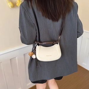 Minimalist white leather crossbody bag with brown strap and baseball charm detail