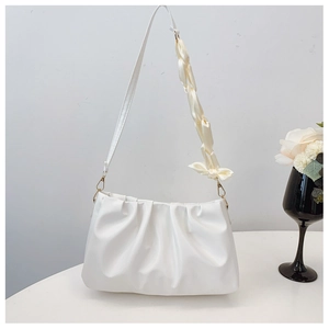 Detail of white pleated cloud bag with silk scarf ribbon and pearl accent on strap