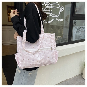 Pink checkered tote bag with star print featuring multiple pockets on a cafe background