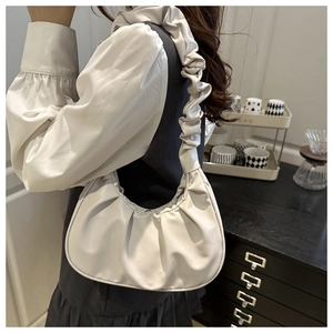 Close-up of white ruched cloud bag with soft pleats and sleek underarm design