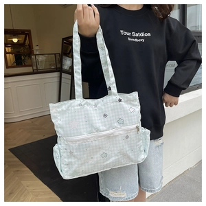 Detail of light blue checkered tote bag with star patterns and spacious side pockets