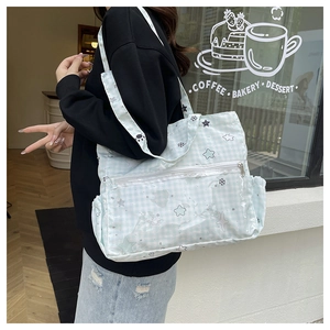 Detail of light blue checkered canvas tote bag with star prints and a wide shoulder strap