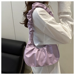 Close-up of lavender pleated cloud bag with scrunchie strap on woman's shoulder