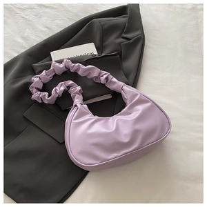 Detailed view of lavender purple pleated shoulder bag on a stylish grey blazer background