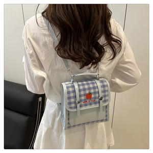 Detail of blue and white plaid backpack featuring red apple embroidery and apple yep text