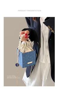 Polka dot denim bucket bag with pearl handle and chain strap shown on model