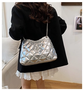 Détail du sac cabas argenté matelassé avec chaîne métallique et rivets sur l'épaule