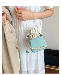 Detail of mint green bucket bag with pearl handle and golden chain shoulder strap