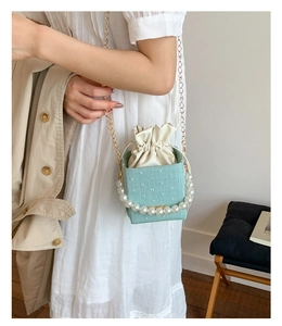 Detail of mint green crossbody square bag with large pearls and golden chain strap