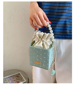 Detail of light green polka dot box bag with elegant pearl handle and gold chain strap