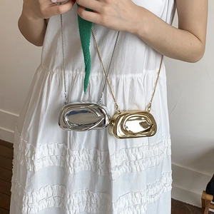Close-up of mini mirrored metal chain bags in glossy gold and silver finishes