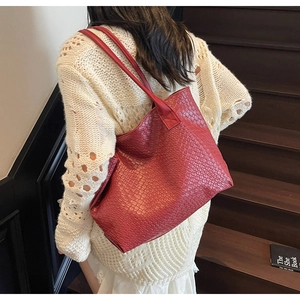 Close-up of red woven texture tote bag worn by a model on a vintage wood staircase