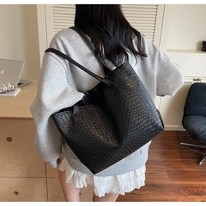 Close-up of black woven leather tote bag showing large capacity and textured details