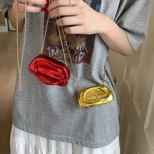 Detail of mini metallic crossbody bags in red and gold finish with gold chain straps