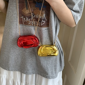 Detail of mini metallic shoulder bags in red and gold with a glossy swirl design
