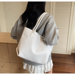 Detailed back view of a large white woven tote bag with shoulder straps on a model