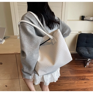 Détail du cabas tressé blanc montrant la texture du cuir et les doubles fines bandoulières
