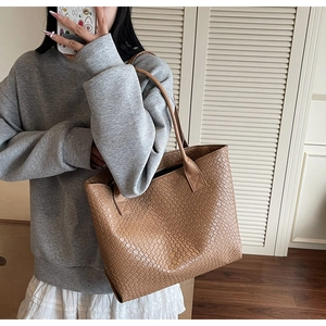 Close-up of caramel woven leather tote bag texture and slim shoulder strap on model