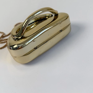 Detail of luxury gold metal evening bag with polished surface and ergonomic handle