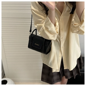 Détail d'un petit sac bandoulière vintage noir avec lettrage FASHION et sangle amovible