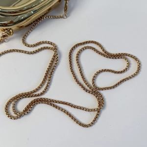 Macro shot of mirror-finish gold metal chain strap with polished circular ring links