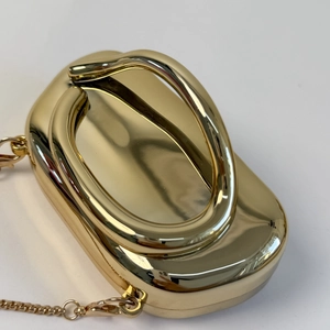 Close-up of golden mirror finish clutch bag with metallic handle and elegant chain strap