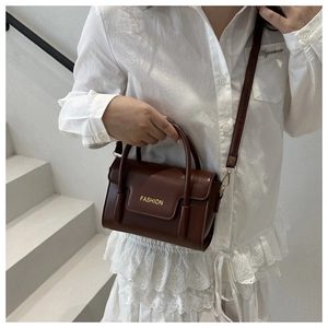 Detailaufnahme der braunen Kunstleder-Tasche mit goldenem FASHION-Schriftzug vor weißem Grund