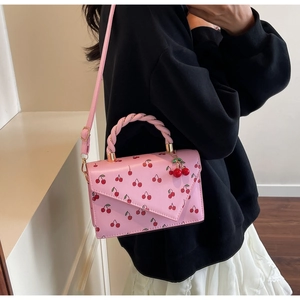 Sac à main rose à imprimé cerise avec poignée tressée et bandoulière réglable sur modèle