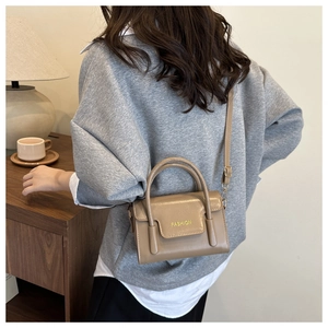 Side view of a khaki PU leather handbag with FASHION text in a cozy indoor setting