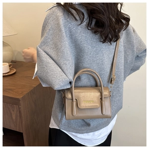 Detail of khaki fashion handbag with yellow lettering and adjustable shoulder strap