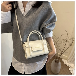 Detail of white faux leather handbag with FASHION lettering and adjustable shoulder strap