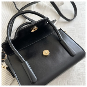 Detail of black matte PU tote bag featuring a round gold magnetic buckle and fine stitching