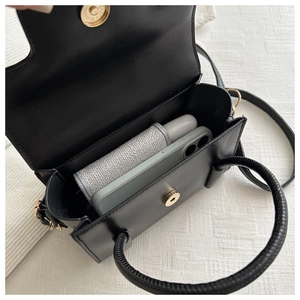 Detail view of black handbag interior showing smartphone capacity and magnetic buckle