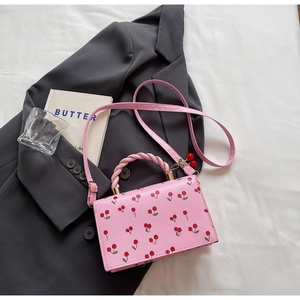 Détail du sac en PU rose à motifs cerises avec poignée torsadée et pendentif cerise
