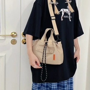 Beige contrast nylon drawstring bucket bag with adjustable strap and front pocket