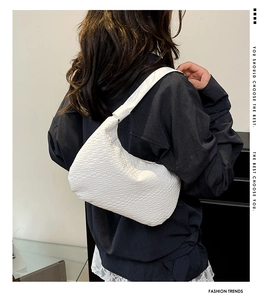 Detail of white woven hobo bag showing the textured material and shoulder strap fit