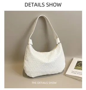 Close-up of white woven hobo bag with intricate lattice texture and smooth handle