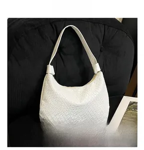 Close-up of white woven hobo bag with intricate lattice texture and smooth handle